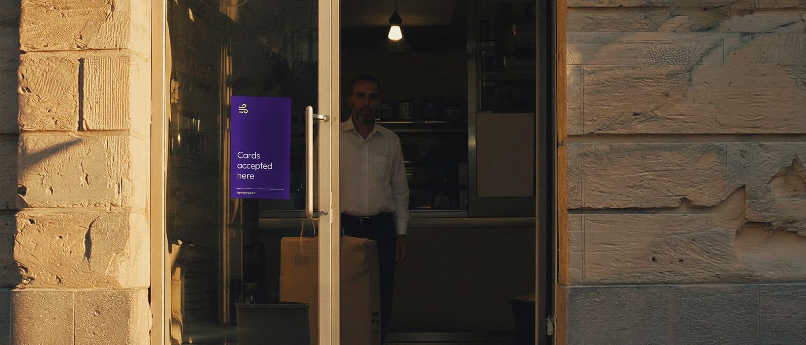 A shop at the end of the day, the shopkeeper inside, and the HawaPay decal in the glass of the door